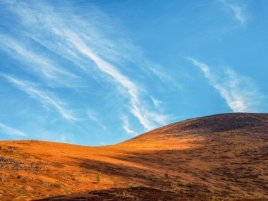 Yamaçlarda altın ışığı olan minimalist, güzel dağ manzarası. Mavi gökyüzünde aydınlatıcı rengi olan manzaralı dağ manzarası.