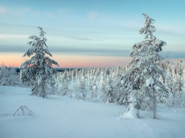 Beautiful Arctic sunset. Scenic colorful sky at dawn. Snow-covered slope of the polar hill in the winter early in the morning. Winter polaris landscape. Dawn of winter silence.