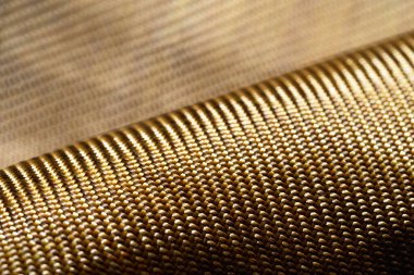 Selective focus. Roll of bulletproof material aramid. Shining aramid kevlar background. Bronze kevlar texture and pattern. 