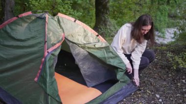 4K 10 bit. Kamp alanında bir çadır kurun. Yürüyüşe çıkmış aktif bir genç kadın. Ormanda iyi tatiller.