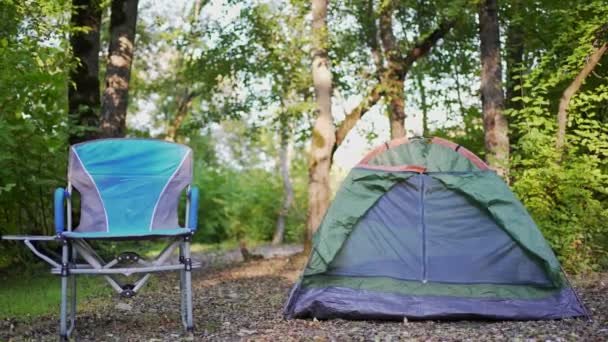 4K 10ビット。キャンプだ。テントや森の中で休息のための椅子。自然の中で穏やかな場所でのレクリエーションとリラクゼーション — ストック動画
