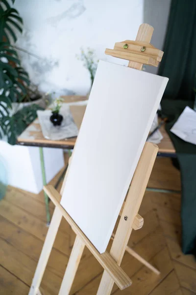 나무로 된 이젤 위에 하얀 캔버스를 펼쳐 놓습니다. 예술가의 방 — 스톡 사진
