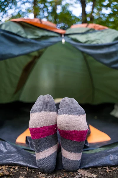 Una mujer con calcetines multicolores brillantes yace en una tienda de campaña en el bosque. Camping. Relajarse en la naturaleza solo — Foto de Stock