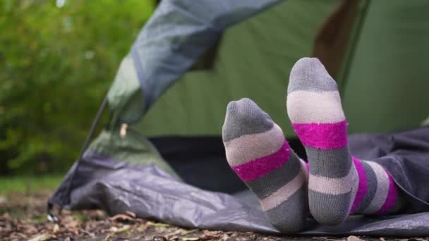 一个穿着鲜艳的多色袜子的女人躺在森林里的一个帐篷里。露营地一个人在野外放松 — 图库视频影像