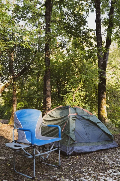 Namiot i składane krzesło w lesie o zachodzie słońca. Odpoczynek i odnowa przyrody — Zdjęcie stockowe