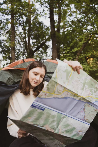 Una turista donna che esplora la mappa seduta in una tenda. Apre una nuova direzione. Itinerario — Foto Stock