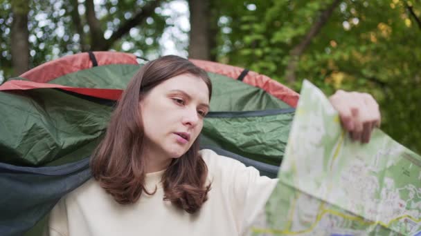 Una turista donna che esplora la mappa seduta in una tenda. Apre una nuova direzione. Itinerario — Video Stock