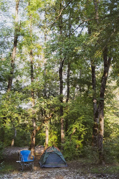 Una pequeña tienda de campaña y una silla para el descanso están en el bosque. Expedición a la naturaleza — Foto de Stock