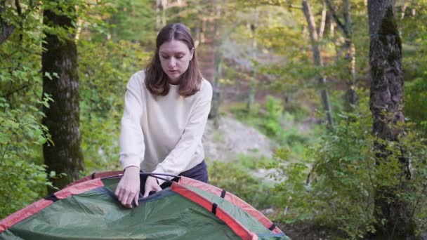 Uma bela turista montou uma tenda. Acampar na floresta. Explore a natureza — Vídeo de Stock
