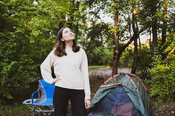 Uma mulher solitária desfruta de umas férias na floresta com uma tenda. Fim de semana na natureza, caminhadas. Jovem turista Fotos De Bancos De Imagens Sem Royalties