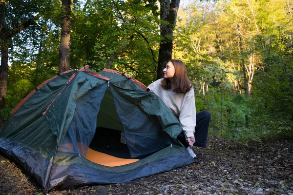 Una giovane turista apre una tenda verde allestita nella foresta. Viaggiare nella natura. Preparare un posto per la notte — Foto Stock