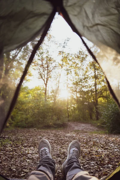 Descanse em uma tenda na floresta. Pés humanos em um acampamento, vista em primeira pessoa Imagens Royalty-Free