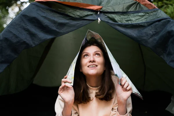 Beautiful young woman fooling around with a map in a tent — Foto Stock