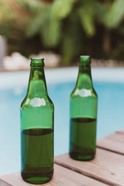 Duas garrafas verdes de cerveja junto à piscina. Festa de Verão Fotos De Bancos De Imagens