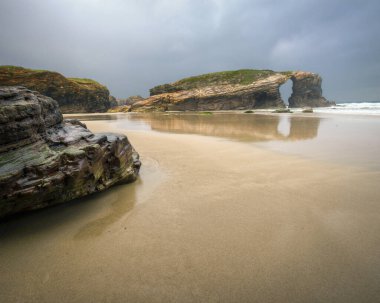Gray and rainy day over the stony arches of As Catedrais beach in Ribadeo Galicia clipart