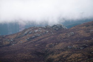 Granitic domes surrounded by heather under low clouds in Xistral Mountain Range in Abadin Lugo Galicia