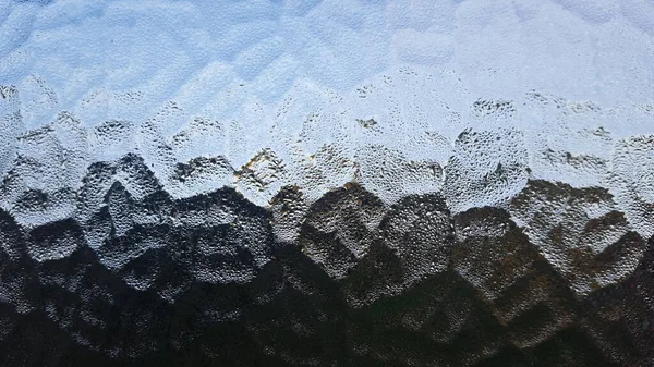 Landscape seen through textured window. Condensation on the glass provides additional texture.