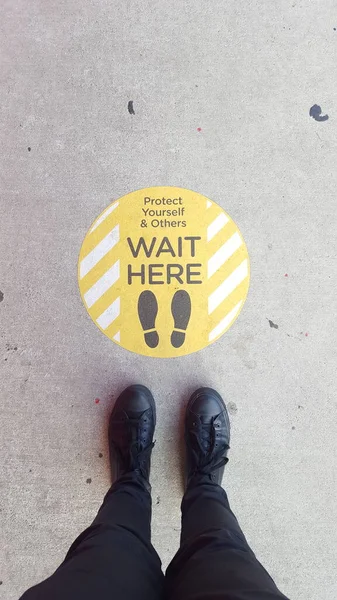 wait here sign and human feet