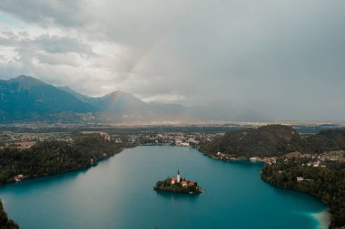 BLED, Slovenya - Ağustos 2022. Slovenya 'da, yağmurlu bir günde gökkuşağıyla Bled Gölü' nün insansız hava aracı resmi.