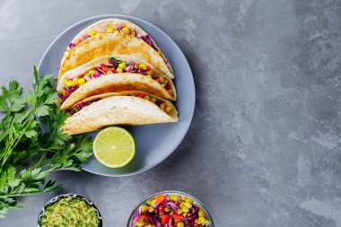 Meksika tacoları, sebzeli ve gri arka planda guacamole. Mısır, mor lahana ve gri tabakta domatesli vejetaryen tacoları. Uzayı kopyala Üst görünüm