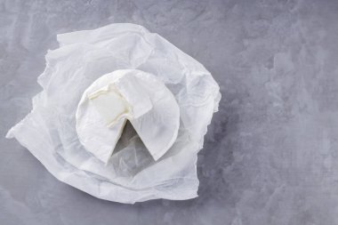 Gri çimento arka planda camembert peyniri. Kağıt üzerinde beyaz küflü yumuşak peynir. Uzayı kopyala Üst görünüm
