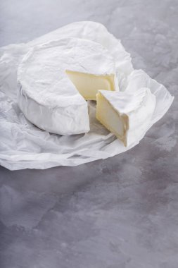 Gri çimento arka planda camembert peyniri. Kağıt üzerinde beyaz küflü yumuşak peynir. Uzayı kopyala Üst görünüm