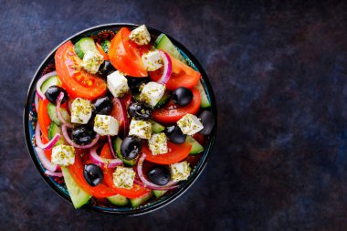 Arka planda bir kasede Yunan salatası. Peynirli ve zeytinli sağlıklı salata. Akdeniz mutfağından taze sebze salatası. Uzayı kopyala Üst görünüm