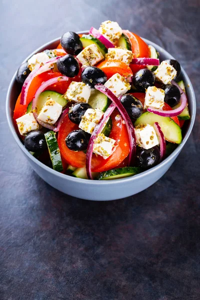 Classic Greek salad with feta and olives on a dark background. Diet and healthy mediterranean salad. Copy space. Top view