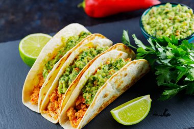 Koyu arkaplanda kızarmış et ve guacamole soslu taco. Meksika tacoları ve malzemeler tahtada. İspanyol yemeği.