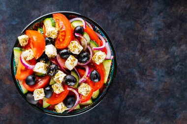 Arka planda bir kasede Yunan salatası. Peynirli ve zeytinli sağlıklı salata. Akdeniz mutfağından taze sebze salatası. Uzayı kopyala Üst görünüm