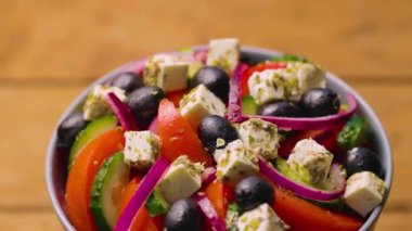 Bir kase Yunan salatası dönüyor. Taze sebzeli salata, peynir ve zeytin. Sağlıklı gıda konsepti. Yakın plan.