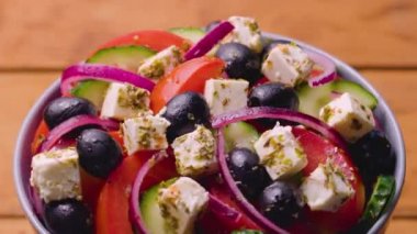 Bir kase Yunan salatası dönüyor. Taze sebzeli salata, peynir ve zeytin. Sağlıklı gıda konsepti. Yakın plan.