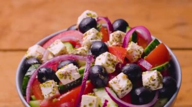 Bir kase Yunan salatası dönüyor. Taze sebzeli salata, peynir ve zeytin. Sağlıklı gıda konsepti. Yakın plan.