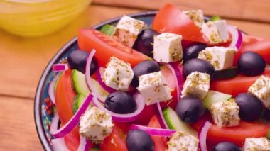 Tahta bir kasede Yunan salatası. Kamera Yunan salatasının üzerinde hareket ediyor. Sebzeli, peynirli ve zeytinli yaz salatası. Elle ateş