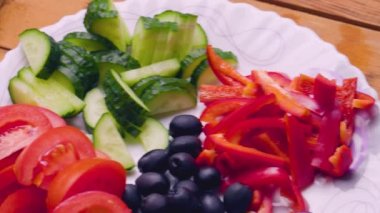Tabakta Yunan salatası için malzemeler. Yaz salatası için taze sebze, peynir ve zeytin. Masanın üzerinde kamera hareketi