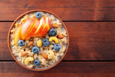 Yabanmersinli yulaf ezmesi, elma ve fındık. Tahta tahtada bir kase yulaf lapası. Sağlıklı kahvaltı konsepti. Üst Manzara. Boşluğu kopyala