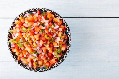 Mexican Pico de Gallo on white boards. Homemade pico de gallo salsa with tomatoes, peppers, jalapenos and red onions. Copy space. Top view