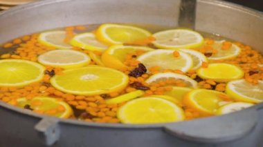 Mulled wine preparation. Warm winter drink with fruits, berries and cinnamon. Traditional Christmas fair market beverage. Close-up