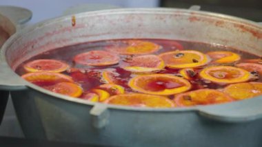 Mulled wine preparation. Warm winter drink with fruits, berries and cinnamon. Traditional Christmas fair market beverage. Close-up