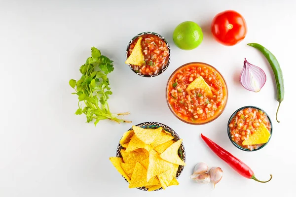Traditional mexican salsa sauce with ingredients on white background. Salsa sauce and nacho chips. Top view. Copy space