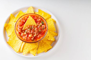 Beyaz tabakta salsa sosu ve cips. Meksika usulü tortilla cipsi ve beyaz arka planda salsa sosu. Üst Manzara. Boşluğu kopyala