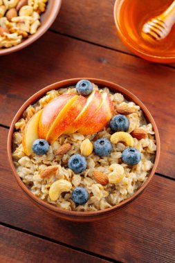 Böğürtlenli, fındıklı ve elmalı lezzetli yulaf ezmesi. Bir kase yulaf lapası, yaban mersini ve bal. Sağlıklı kahvaltı. Üst görünüm