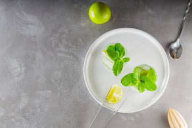 Mojito kokteyli ve gri arka planda bar aksesuarları. Beyaz bir tabakta iki bardak mojito. Yaz ferahlatıcı limon ve naneli kokteyl. Boşluğu kopyala