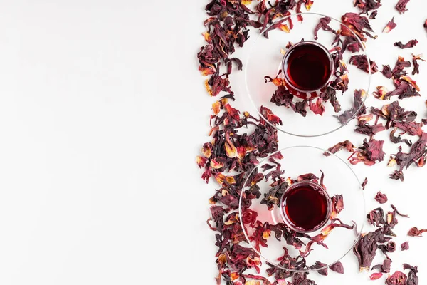 Hibiscus tea in traditional Turkish glasses on a white background. Hibiscus tea and dry hibiscus petals. Top view. Copy space