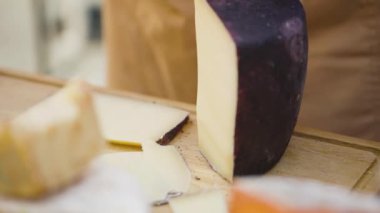 Siyah eldivenli satıcı peyniri kesiyor. Tadına bakmak için peyniri küçük parçalara ayırma süreci. Süt ürünleri satış kavramı