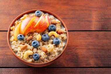Yabanmersinli yulaf ezmesi, elma ve fındık. Tahta tahtada bir kase yulaf lapası. Sağlıklı kahvaltı konsepti. Üst Manzara. Boşluğu kopyala