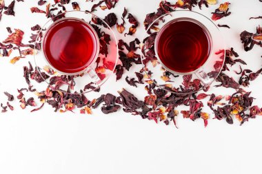 Beyaz arka planda bir fincan amberçiçeği çayı (rosella, karkade, kırmızı kuş). Hibiscus çayı ve kuru amber yaprağı. Bitkilerle birlikte idrar söktürücü içecek. Üst Manzara. Boşluğu kopyala