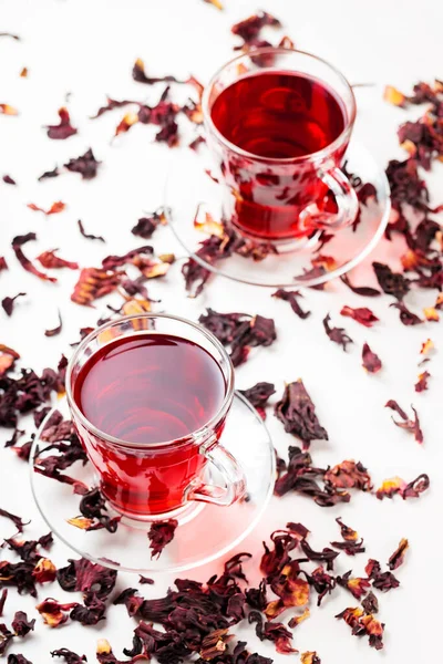 Cup of hibiscus tea (rosella, karkade, red sorrel) on a white background. Hibiscus tea and dry hibiscus petals. Diuretic drink with herbs. Top view. Copy space