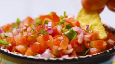 Pico de Gallo 'yu kapatın. Geleneksel pico de gallo tabağına tortilla cipsi batırıyorum. Bir kase lezzetli Pico de Gallo salsa ve cips. Meksika yemeği konsepti
