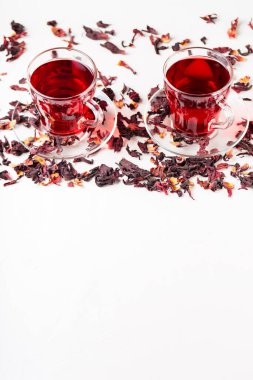 Beyaz arka planda bir fincan amberçiçeği çayı (rosella, karkade, kırmızı kuş). Hibiscus çayı ve kuru amber yaprağı. Bitkilerle birlikte idrar söktürücü içecek. Üst Manzara. Boşluğu kopyala